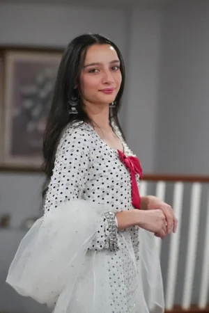 Full-length view of a dazzling rose pink or magenta shamoz silk sharara set with a detailed short-sleeved top, flared sharara pants, and a sheer tulle dupatta. The outfit features intricate hand embroidery or mirror work, showcasing the South Asian craftsmanship of the Summer Sekhon brand.